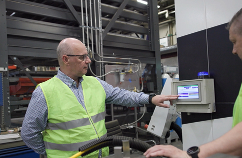 Två medarbetare i industrimiljö använder digital styrpanel och produktionssystem för övervakning, kvalitetskontroll och effektiv tillverkning