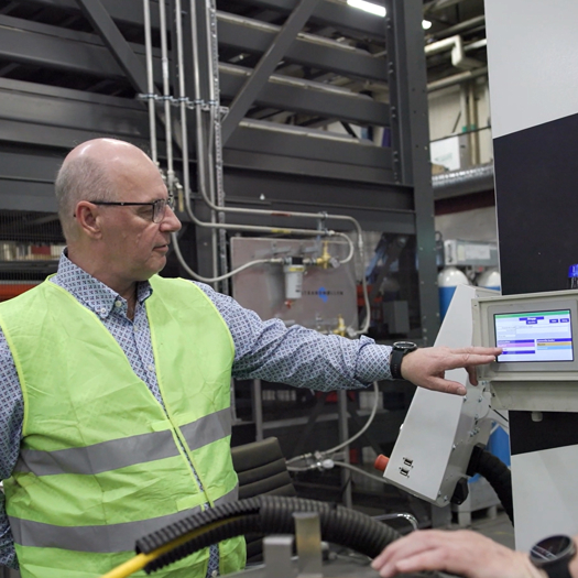 Två medarbetare i industrimiljö använder digital styrpanel och produktionssystem för övervakning, kvalitetskontroll och effektiv tillverkning