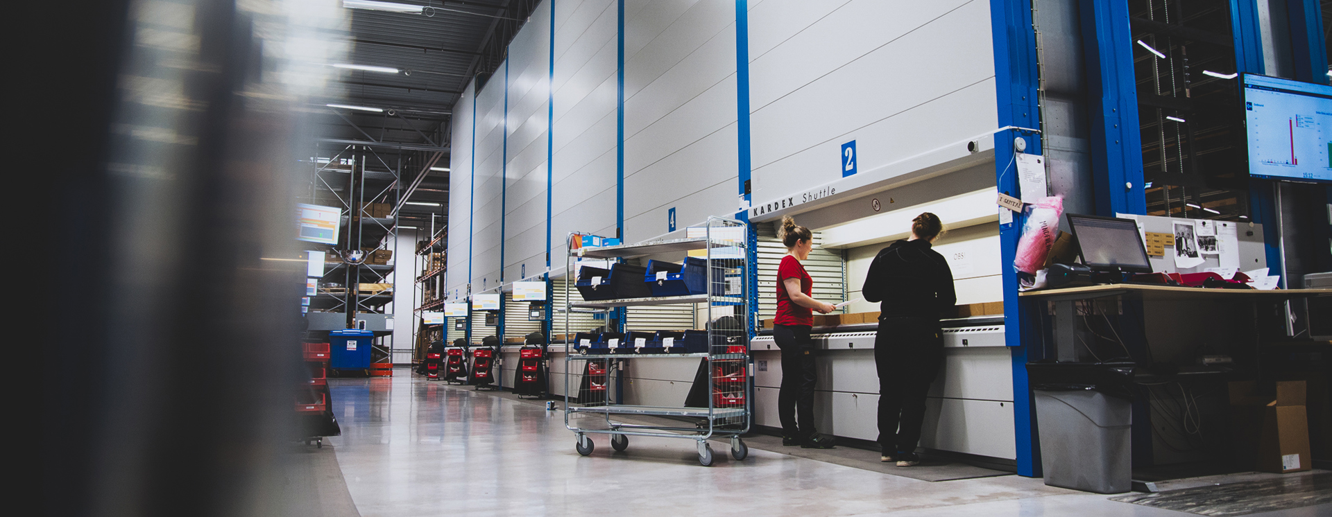 Medarbetare på OEM International arbetar vid automatiserade lagerautomater i modern logistik- och produktionsmiljö med fokus på effektiv lagerhantering och verksamhetsstyrning
