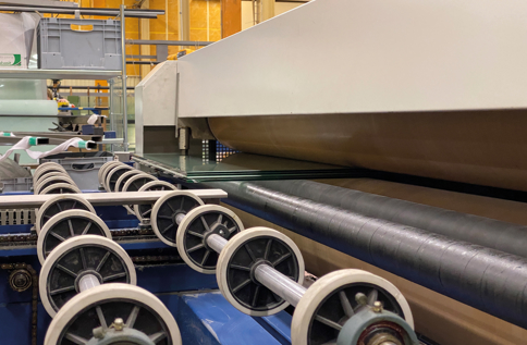 Automatiserad glasbearbetning i produktionslinje där glasrutor transporteras genom industriell maskinutrustning för tillverkning och förädling