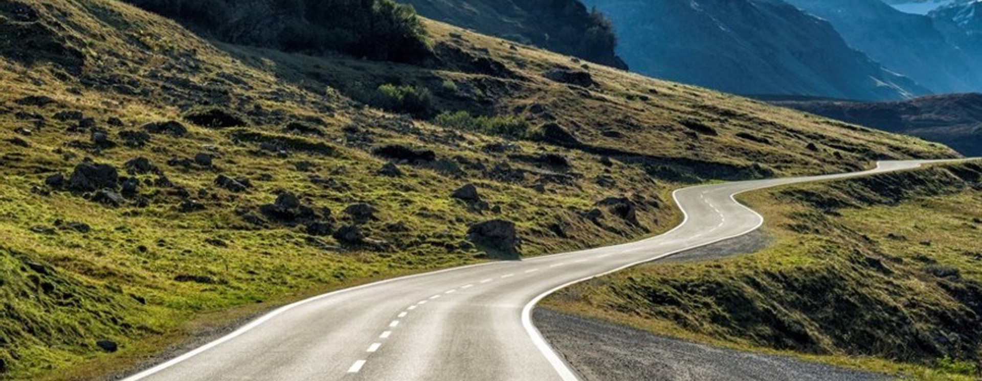 Slingrande väg genom bergslandskap med dalar och natur som symboliserar resa, utveckling och långsiktig strategi inom digital transformation