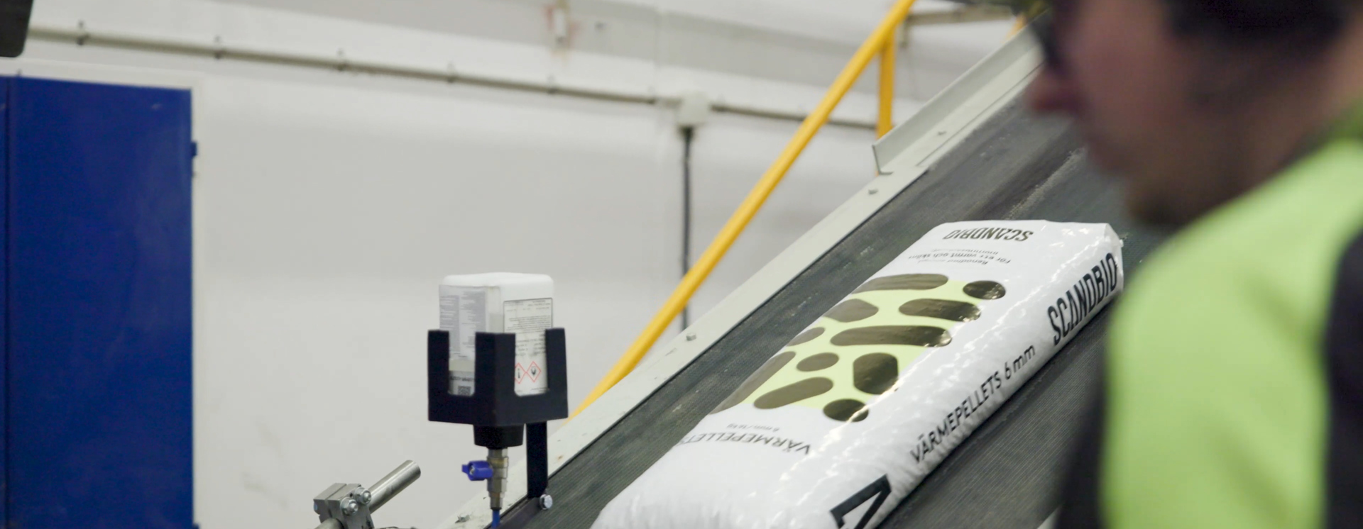 Säck med Scandbio träpellets transporteras på produktionslinje i industriell miljö med fokus på hållbar bioenergi och effektiv tillverkning