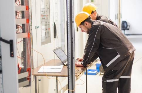 Tekniker Arbetar Vid Elskåp Med Bärbar Dator Under Service Och Felsökning I Industriell Miljö