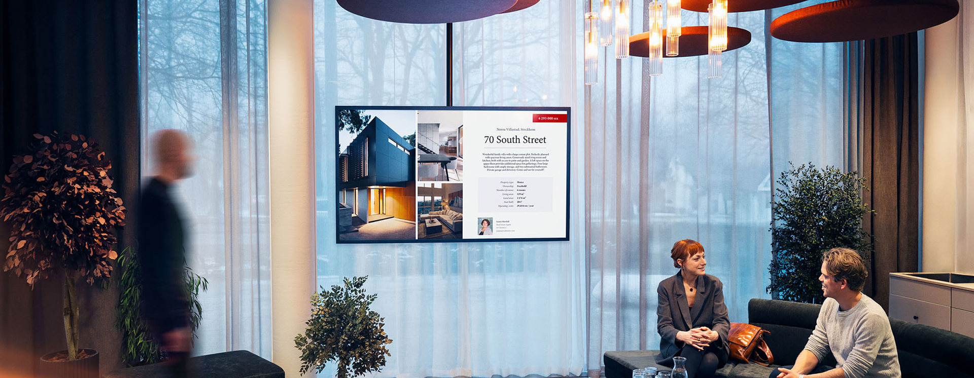 Digital informationsskärm i modern lobby visar fastighetsinformation och innehåll via Smartsign, medan besökare vistas i gemensam lounge- och receptionsmiljö