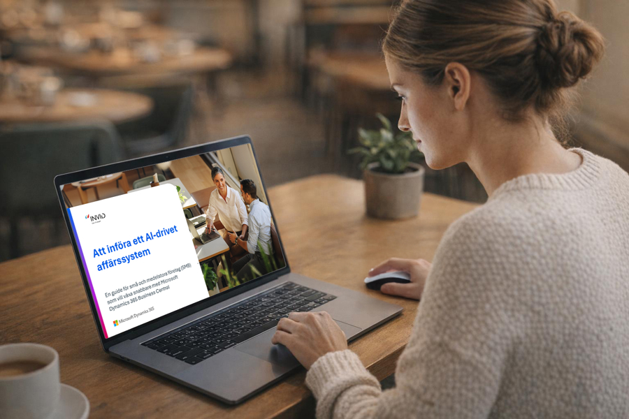 Person arbetar vid laptop i café- eller kontorsmiljö och läser e‑bok om att införa ett AI‑drivet affärssystem med Microsoft Dynamics 365 Business Central för digitalisering och verksamhetsutveckling