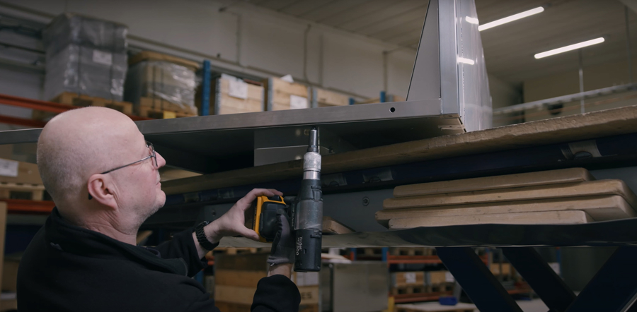 Medarbetare monterar industriell utrustning med elverktyg i produktionsmiljö med fokus på tillverkning, kvalitet och effektiv produktion