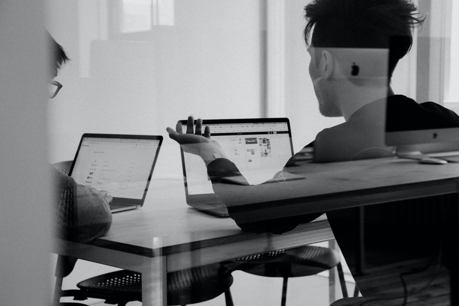 Två personer arbetar vid laptop i mötesrum och diskuterar digitala lösningar och affärssystem, vilket visar samarbete, analys och proaktiv IT‑hantering i verksamheten