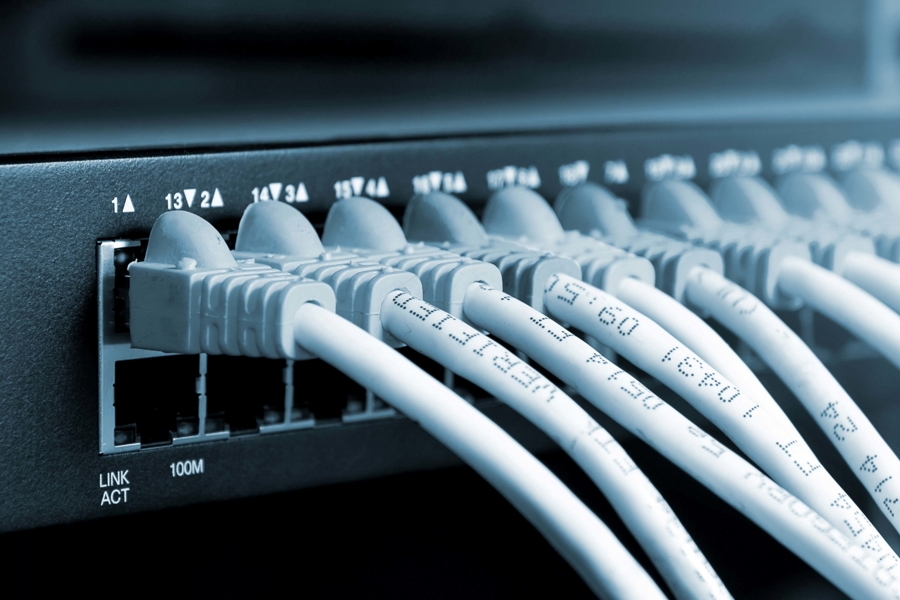 Närbild av nätverkskablar anslutna till switch med flera portar och indikatorlampor, vilket illustrerar serverdrift som tjänst, stabil nätverksinfrastruktur, datakommunikation och säker drift av IT‑miljö