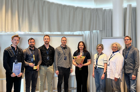 Gruppbild från Pyramid-konferens där deltagare uppmärksammas med diplom, blommor och prisutdelning på scen