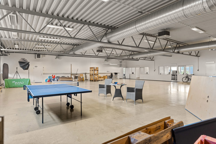 Stor Och Ljus Produktions Och Lagerlokal Med Hogt Tak Synliga Ventilationsror Och Stora Oppna Ytor I Lokalen Finns Bland Annat Pingisbord Sittgrupp Arbetsplatser Och Forvaringspallar (1)