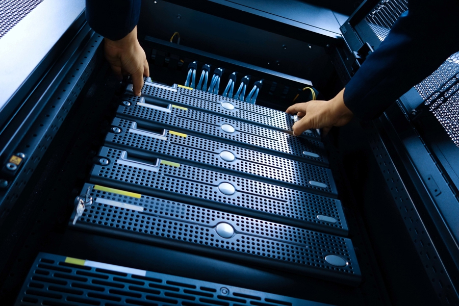 Närbild av händer som installerar och hanterar servrar i rack i datacenter, vilket illustrerar klientdrift som tjänst, hårdvaruhantering, IT‑infrastruktur och drift av affärskritiska system i modern servermiljö