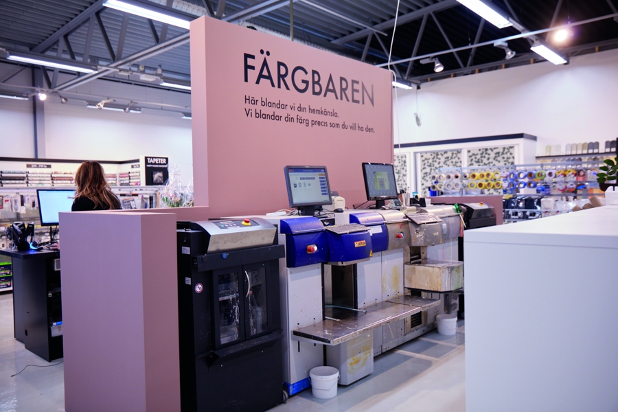 Färgbar i Happy Homes-butik med automatiserade färgblandningsmaskiner för kundanpassad toning av färg och måleriprodukter