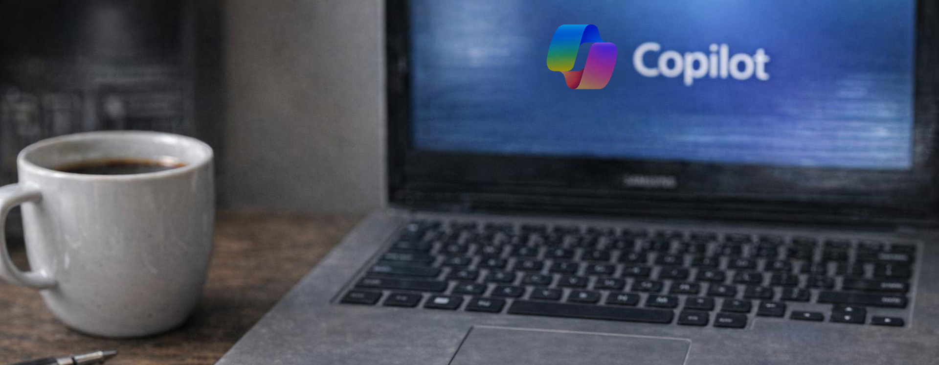 Närbild av en laptop på ett skrivbord med Copilot‑logotyp på skärmen, bredvid en kaffekopp och en penna