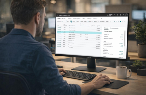 Person arbetar vid dator med Microsoft Dynamics 365 Business Central på stor skärm och hanterar kunddata, order och ekonomi i digitalt affärssystem i modern kontorsmiljö