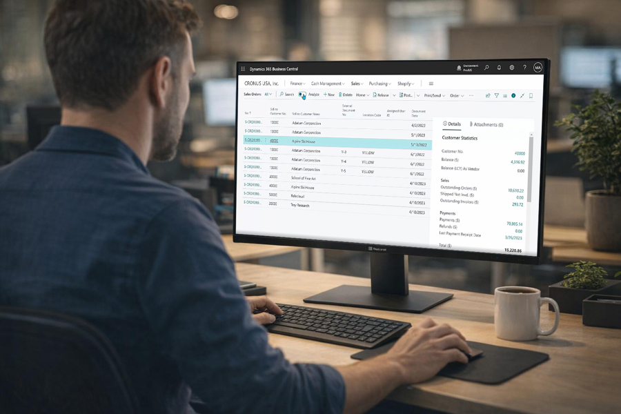 Person arbetar vid dator med Microsoft Dynamics 365 Business Central på stor skärm och hanterar kunddata, order och ekonomi i digitalt affärssystem i modern kontorsmiljö