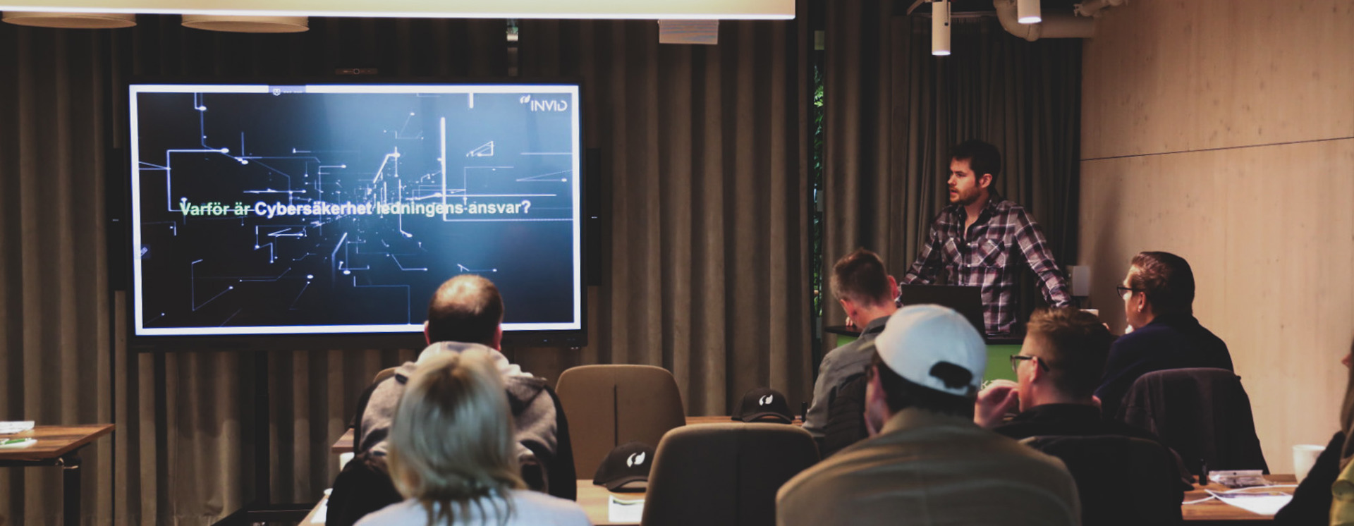 Robin Rosengren presenterar om cybersäkerhet inför sittande publik med projektorskärm och presentation i konferensrum