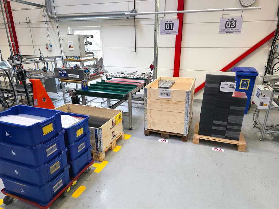 Produktionslokal hos Kortsystem med maskiner, blå plastlådor och pallar