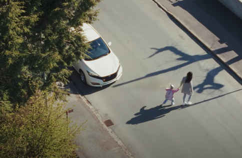 Person och barn passerar gata vid bil, fokus på trygghet och cybersäkerhet