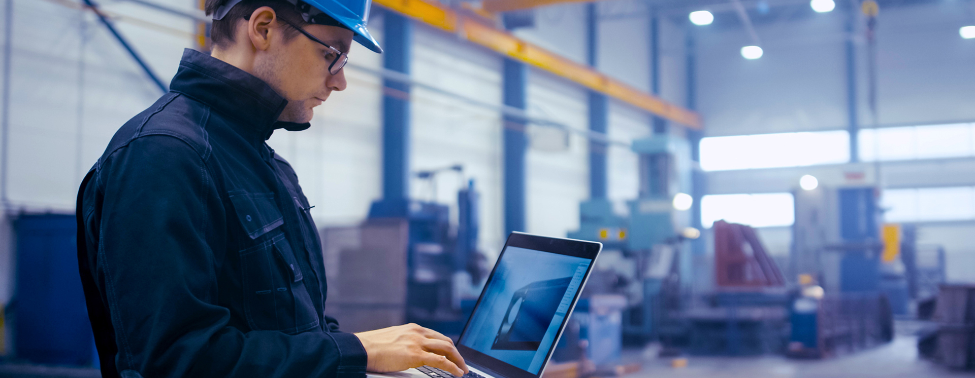Stock Photo Factory Worker In A Hard Hat Is Using A Laptop Computer With An Engineering Software 702079537